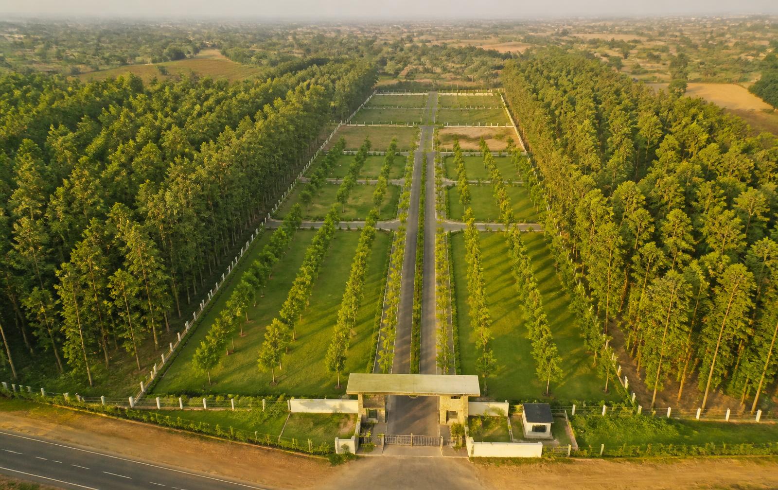 Aerial view of the Project 4 Malavalli managed teak farmland estate with plantation blocks, demarcated farm plots, internal roads and the gated entrance